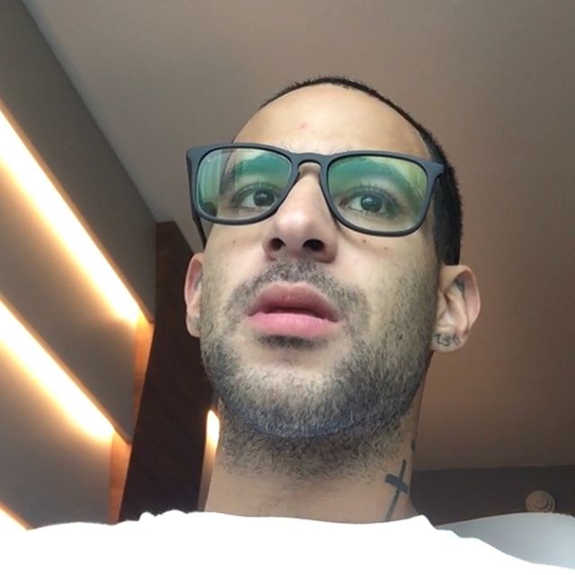 Cristian Marcus Muniz's brother in a white t-shirt and black framed spectacles.